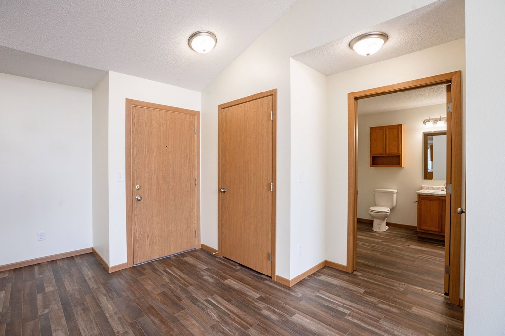 A room with two doors and a bathroom visible through one of the doors. Bismarck, ND Sierra Ridge Apartments