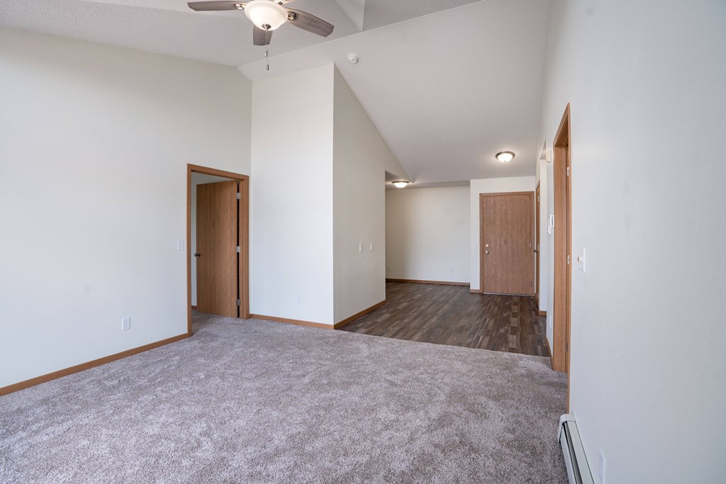 A room with a grey carpet and wooden doors. Bismarck, ND Sierra Ridge Apartments