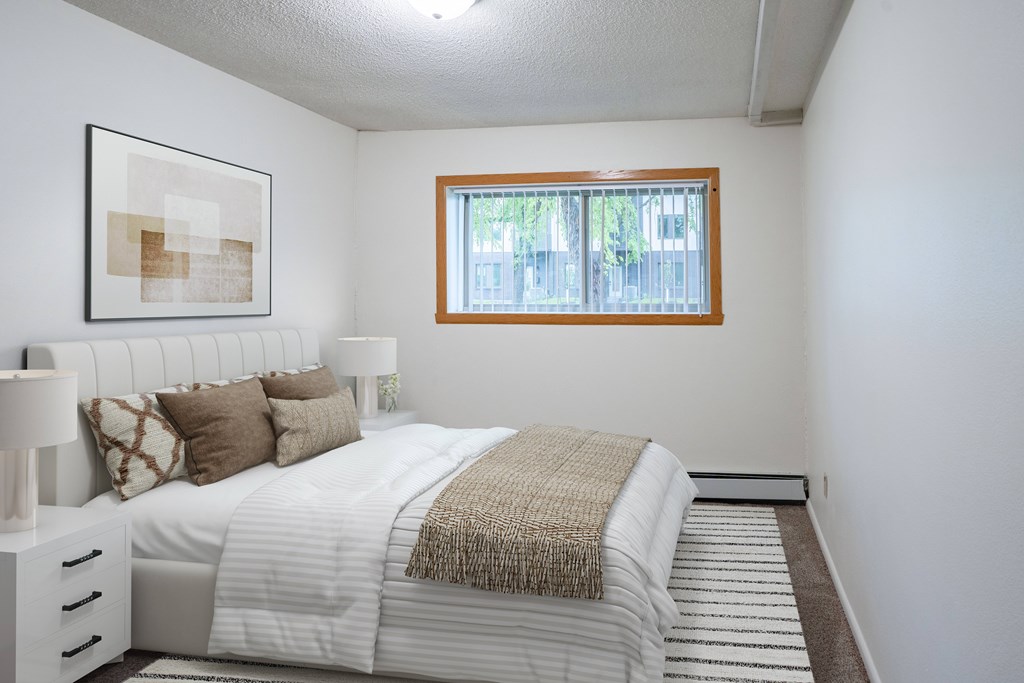 A bedroom with a large bed and a window. Fargo, ND Park Terrace Apartments