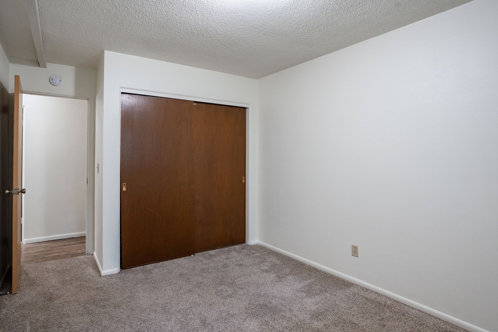 A room with a brown door and carpeted floor. Fargo, ND Park Terrace Apartments