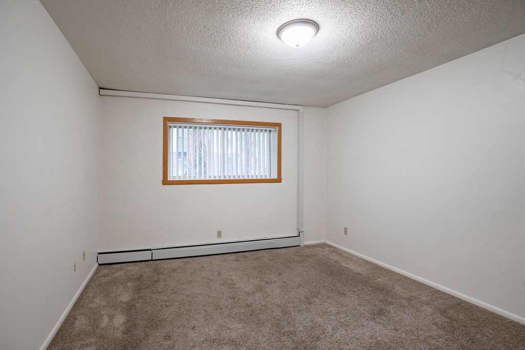 A room with a window and carpeted floor. Fargo, ND Park Terrace Apartments