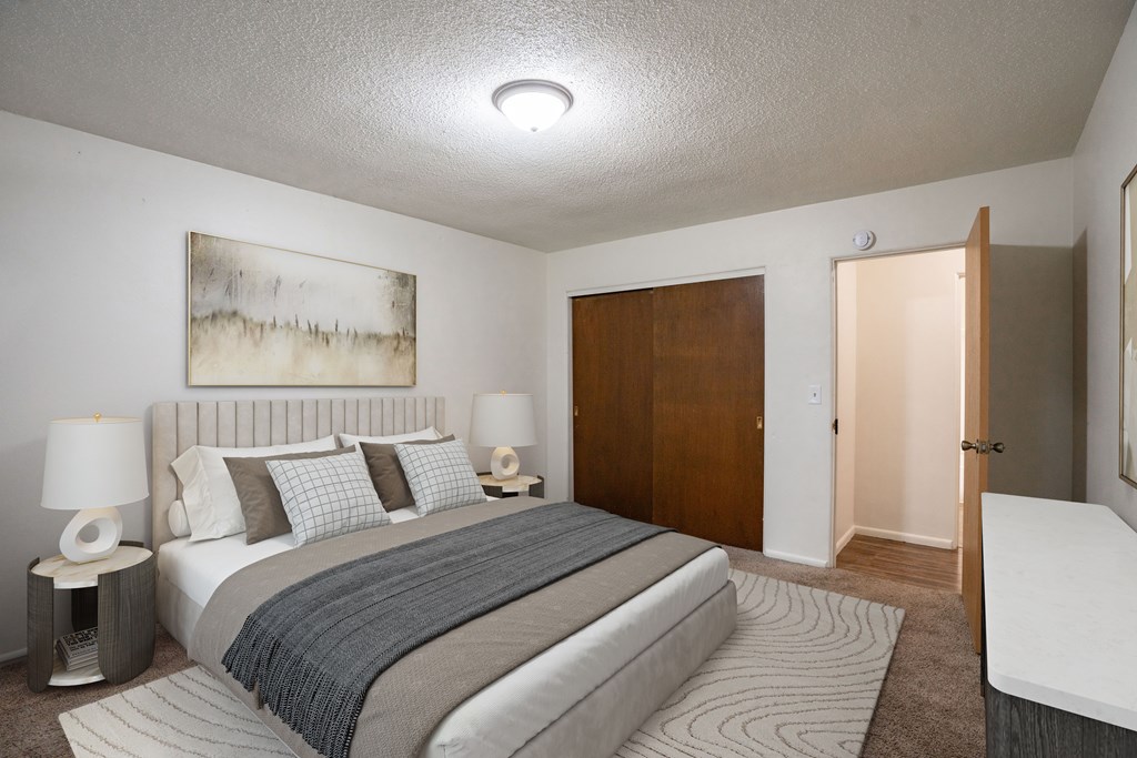 A bedroom with a large bed and a painting on the wall. Fargo, ND Park Terrace Apartments