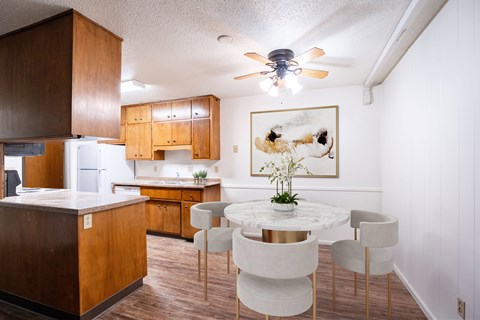 A kitchen with a table and chairs in front of a painting of a cow.