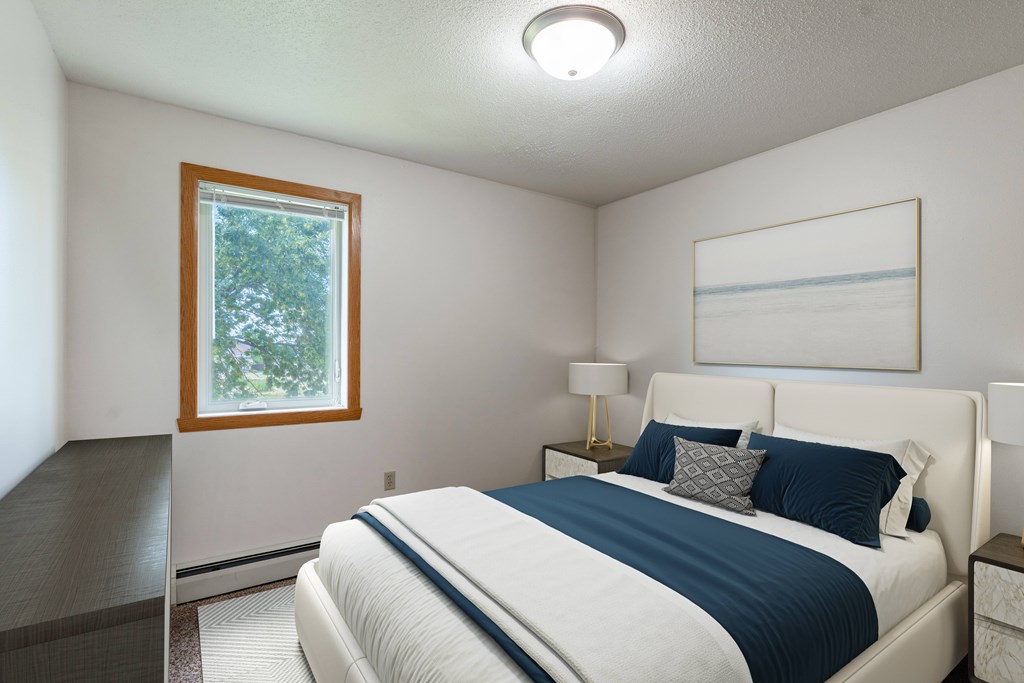 A bedroom with a bed, nightstands, and a window. West Fargo, ND Clearview Apartments