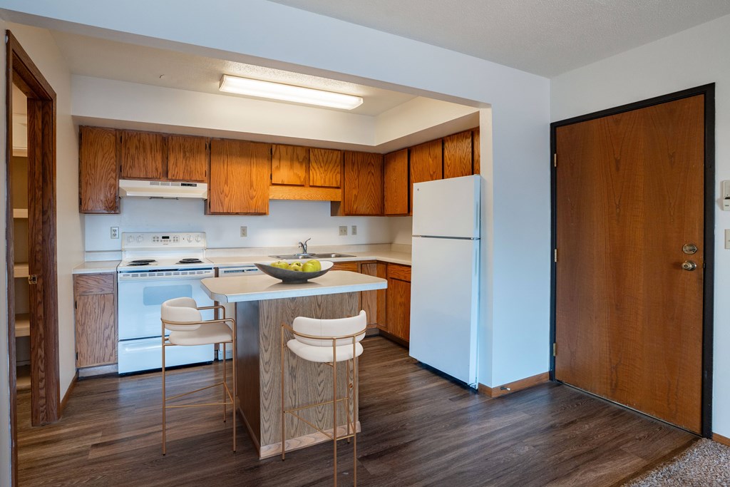 A kitchen with wooden cabinets and a white fridge. West Fargo, ND Clearview Apartments
