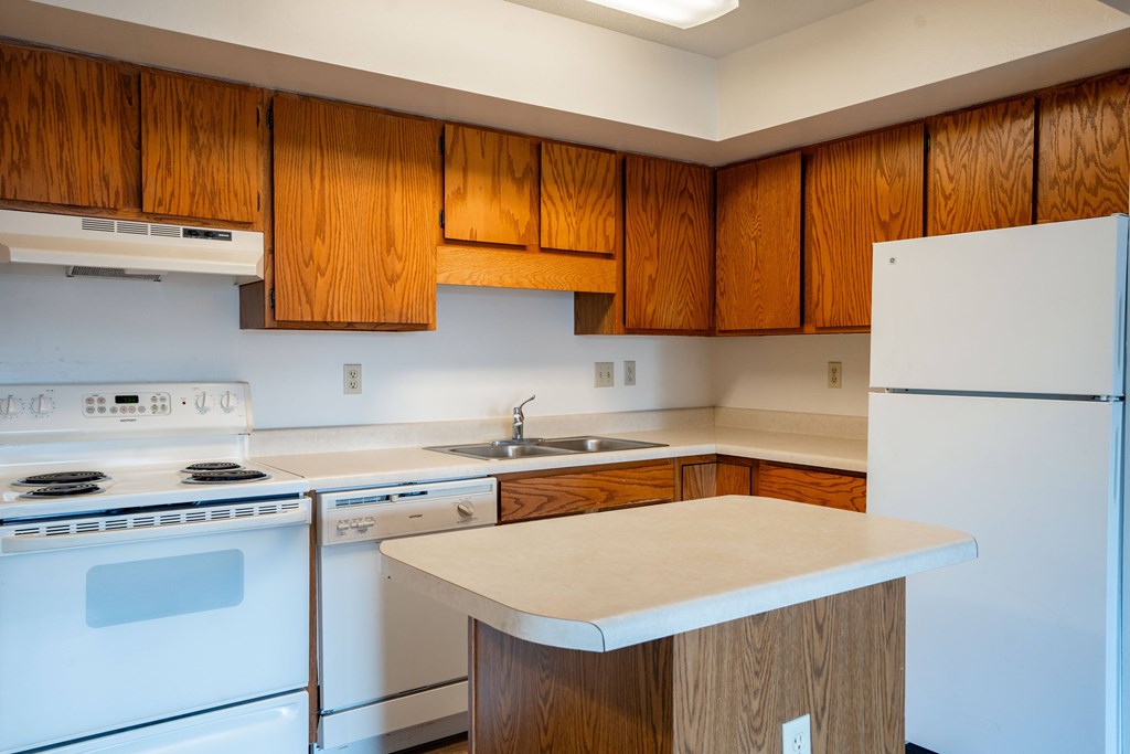 A kitchen with a white stove and white refrigerator. West Fargo, ND Clearview Apartments