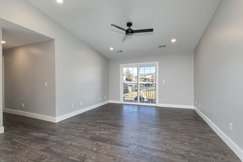 spacious living room with hardwood floors and sliding glass door at Quail Creek Apartments