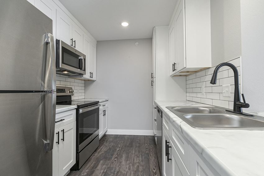 kitchen with stainless steel appliances and hardwood floors at Quail Creek Apartments
