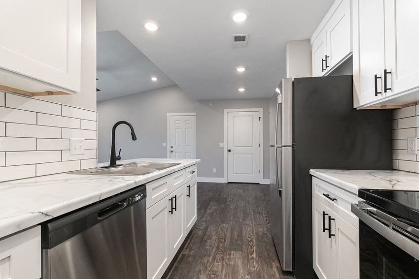 kitchen with white countertops and hardwood floors at Quail Creek Apartments - Photo Gallery 1