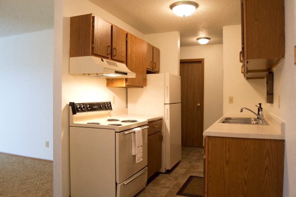 Fargo, ND Candlelight Apartments | Kitchen a kitchen with a stove refrigerator and a sink. Fargo, ND Candlelight Apartments