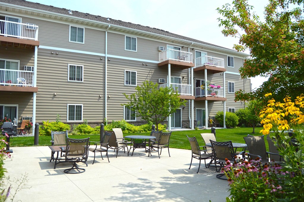 a patio with tables and chairs in front of an apartment building