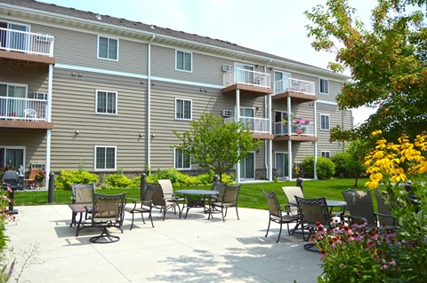 Fargo, ND Crossroads Apartments | Exterior The exterior of a three level apartment building with a grass and patio area out front. Fargo, ND Crossroads Apartments