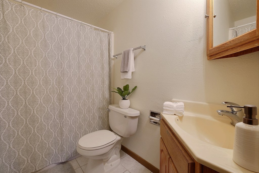 a bathroom with a toilet and a sink. Fargo, ND Alden Pines Apartments