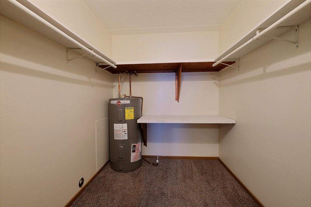 a small room with shelves and a water heater. Fargo, ND Alden Pines Apartments.