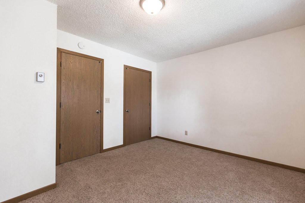 Bismarck, ND Arbor 400 Apartments | Bedroom Bismarck, ND Arbor 400 Apartments. A bedroom with a carpeted floor and a wooden door