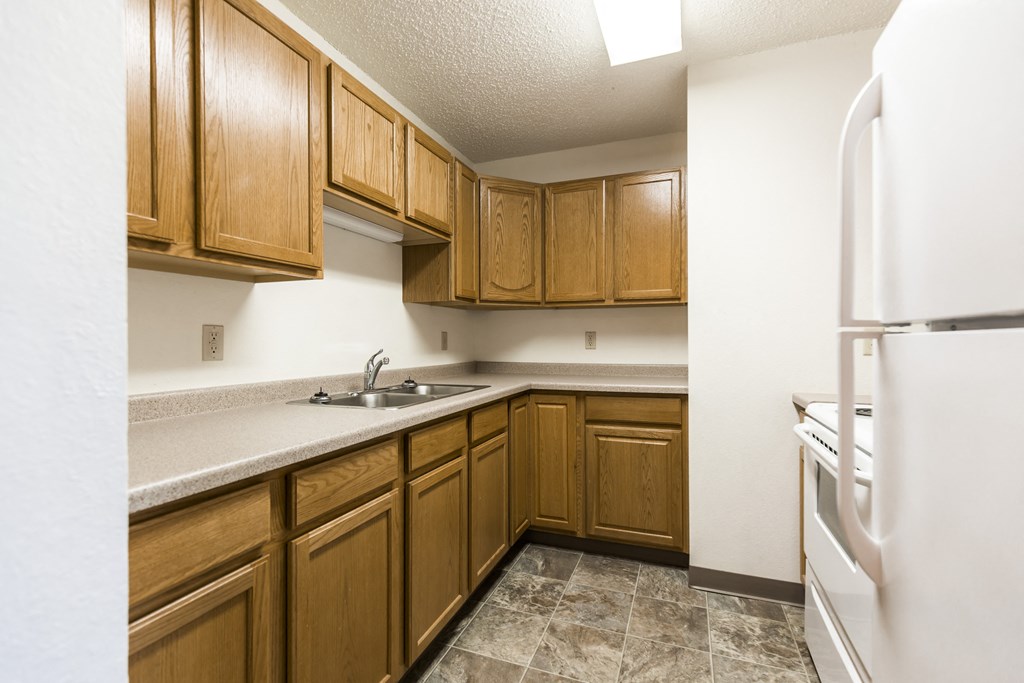 Bismarck, ND Arbor 400 Apartments. A kitchen with wooden cabinets and white appliances