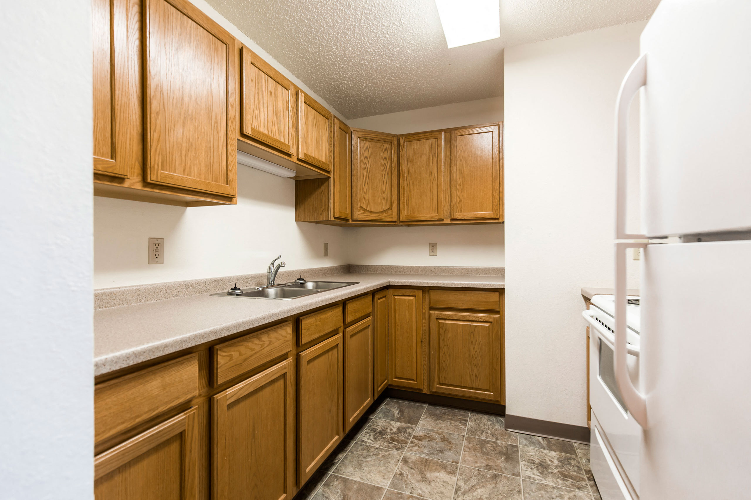 a kitchen with wooden cabinets and a sink and a refrigerator