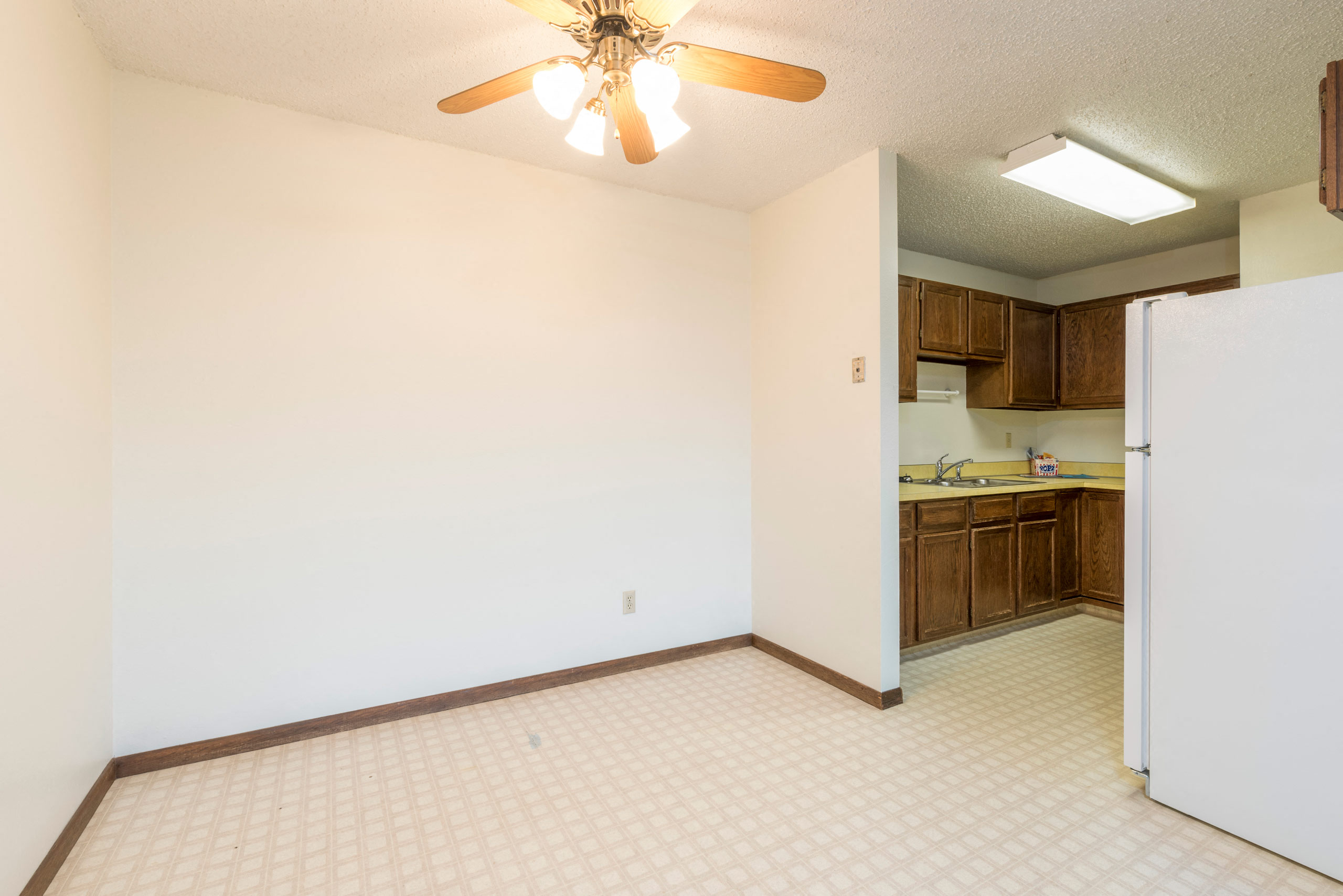 a kitchen with a refrigerator and a ceiling fan