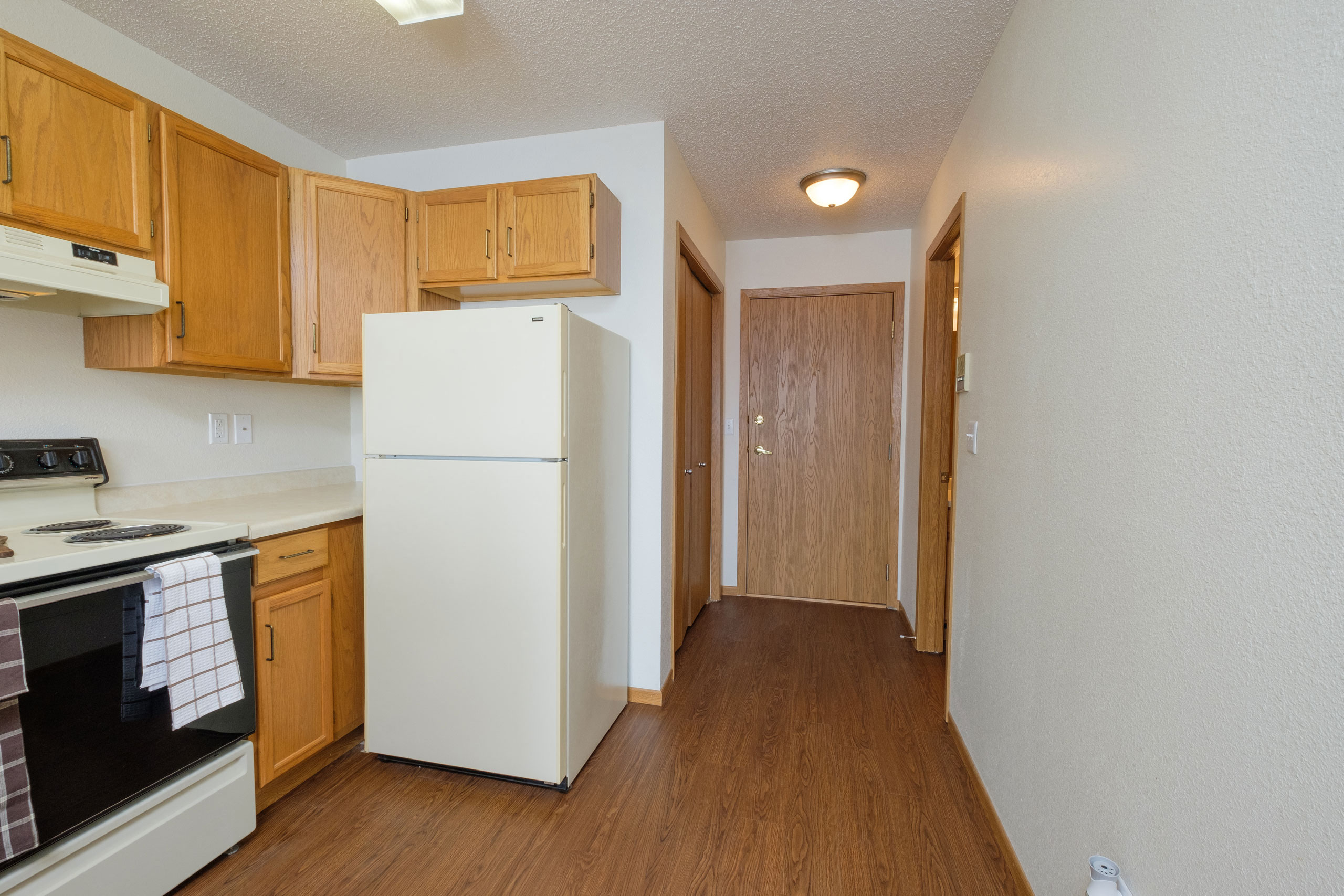 a kitchen with a white refrigerator and wooden cabinets     and a door