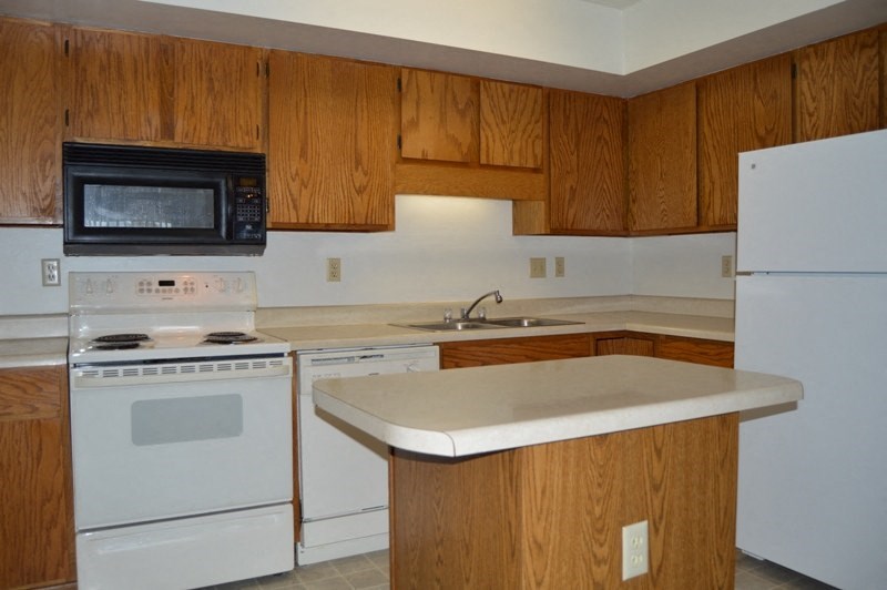 a kitchen with white appliances and wooden cabinets