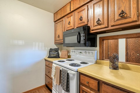 a kitchen with a stove and microwave and wooden cabinets