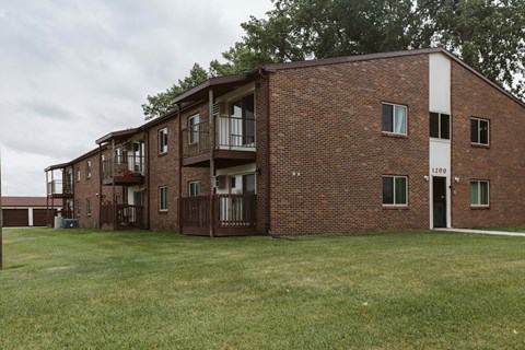 Grand Forks, ND Barrette Arms Apartments. a large brick apartment building with a large grassy area in front of it