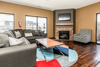 A living room with a grey couch, a fireplace, and a television.