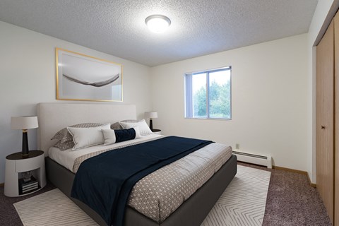 a bedroom with a bed and a window. Bismarck, ND Belmont East Apartments
