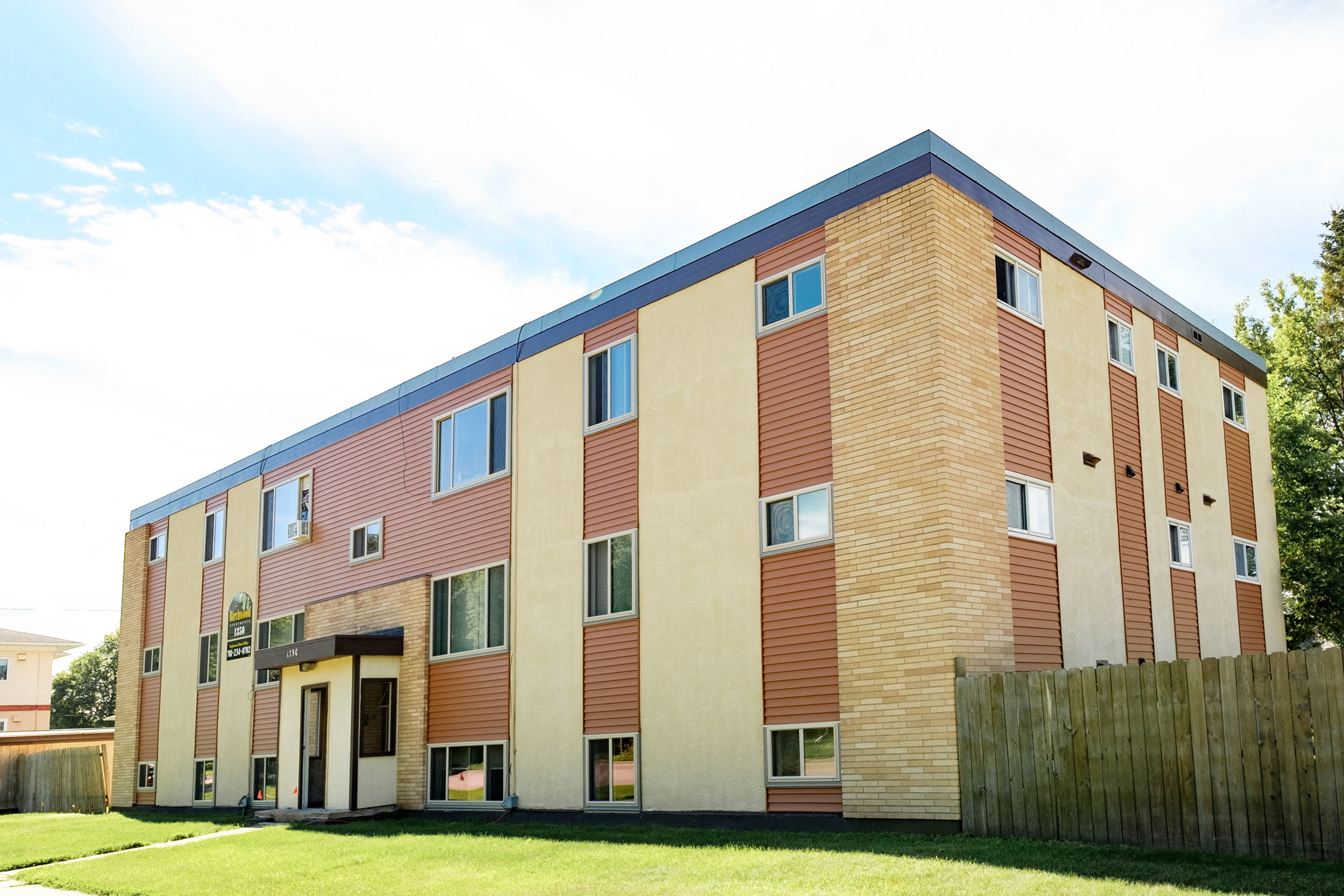 the exterior of a brick apartment building with a green yard