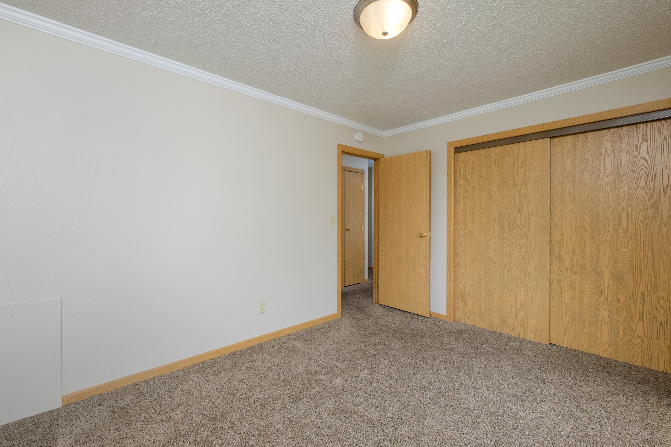 a bedroom with a closet and carpeted floors. Fargo, ND Birchwood 2 Apartments