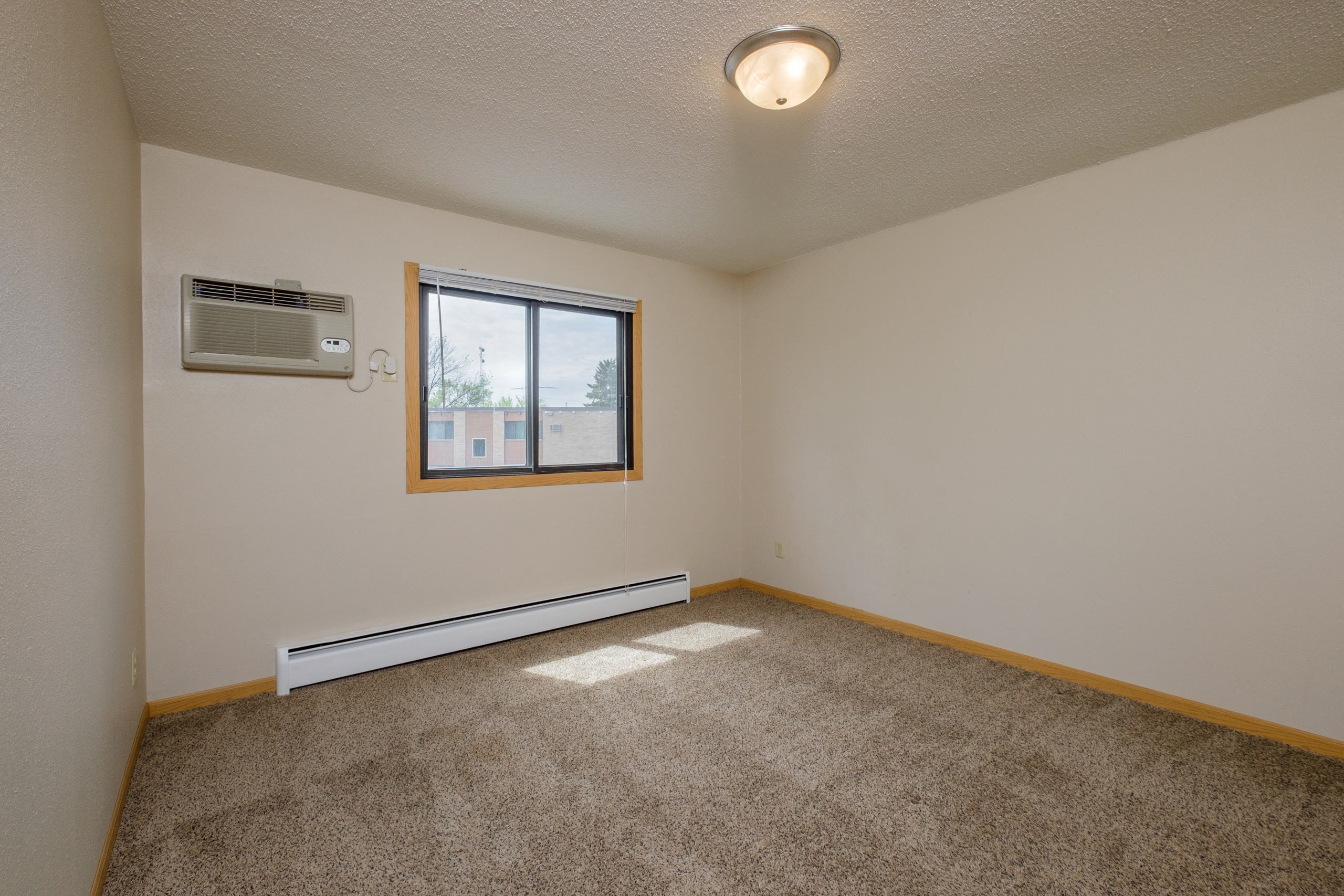 a bedroom with a window and a carpeted floor. Fargo, ND Birchwood 2 Apartments