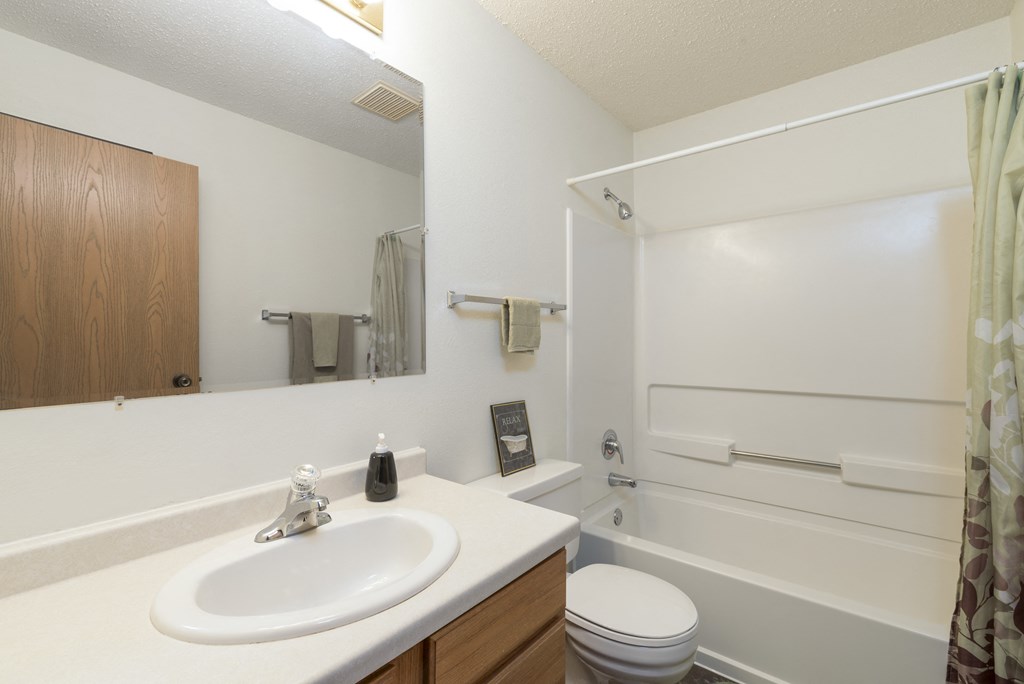 a bathroom with a sink and a toilet and a shower. Bismarck, ND Bradbury Apartments