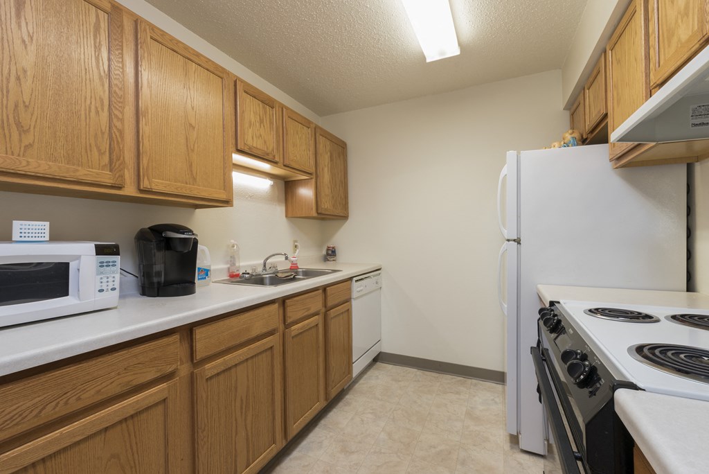 Bismarck, ND Bradbury Apartments | Kitchen a kitchen with white appliances and wooden cabinets. Bismarck, ND Bradbury Apartments
