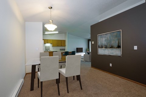 a dining area in a two bedroom apartment with a dark gray wall and a four chair table. Fargo, ND Bridgeport Apartments