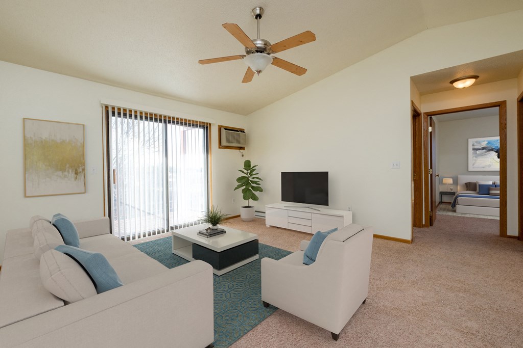 a living room with a couch, coffee table, and tv with a glass sliding door with plenty of natural light.Fargo, ND Bridgeport Apartments