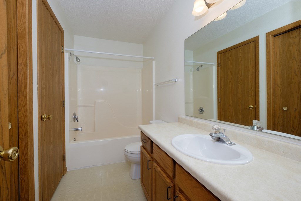 a bathroom with a sink and a toilet and a shower. Fargo, ND Bridgeport Apartments