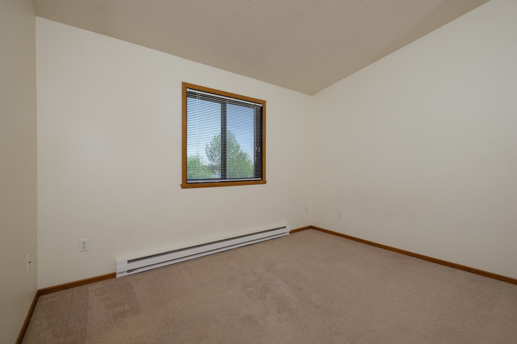 a bedroom with a window and baseboard heater. Fargo, ND Bridgeport Apartments