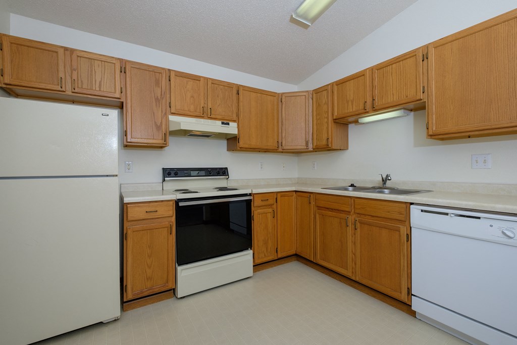 a kitchen with white appliances and wooden cabinets. Fargo, ND Bridgeport Apartments