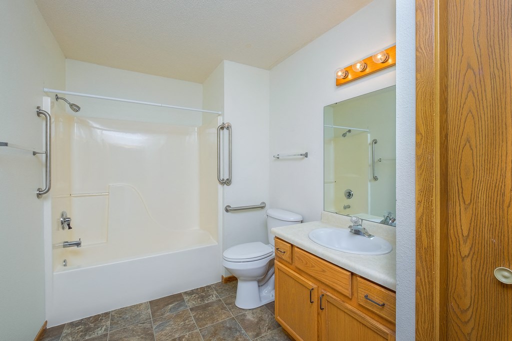a bathroom with a sink and a toilet and a shower. Fargo, ND Bridgeport Apartments