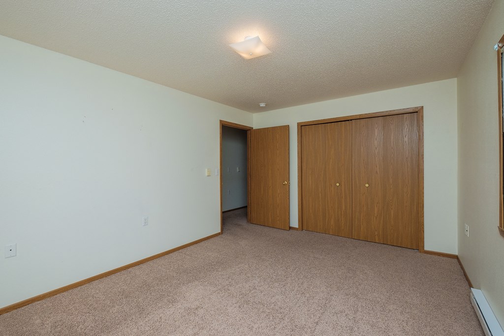 a bedroom with a closet and carpeted floors. Fargo, ND Bridgeport Apartments