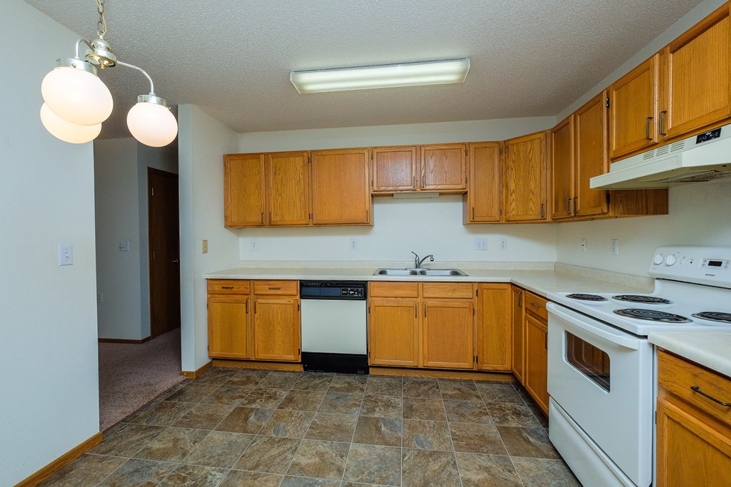 a kitchen with white appliances and wooden cabinets. Fargo, ND Bridgeport Apartments