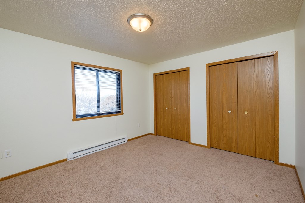 a  bedroom with two closets and a window. Fargo, ND Bridgeport Apartments