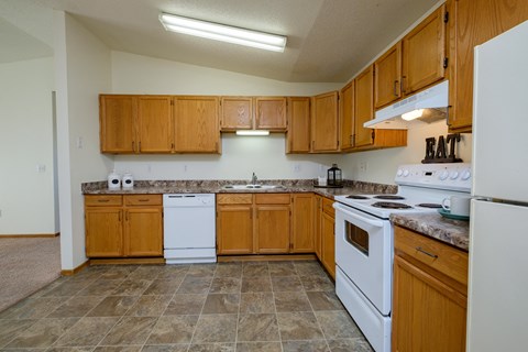 a kitchen with white appliances and wooden cabinets. Fargo, ND Bridgeport Apartments
