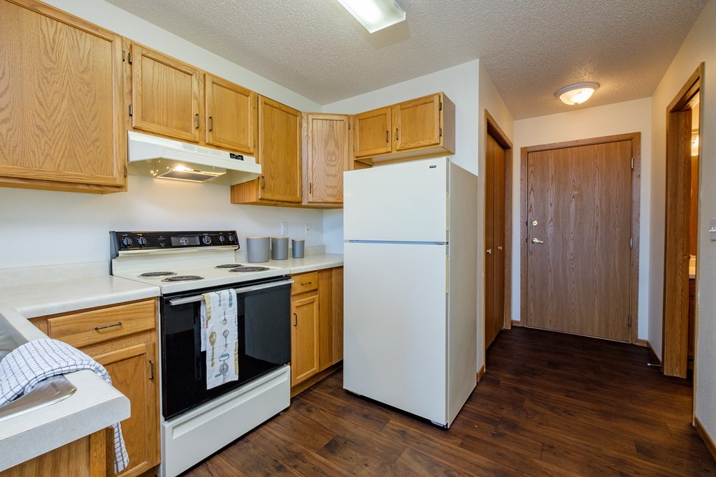 a kitchen with white appliances in an efficiency apartment. Fargo, ND Bridgeport Apartments