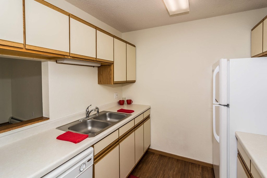 Grand Forks, ND Bristol Park Apartments. a kitchen with white appliances and wooden cabinets