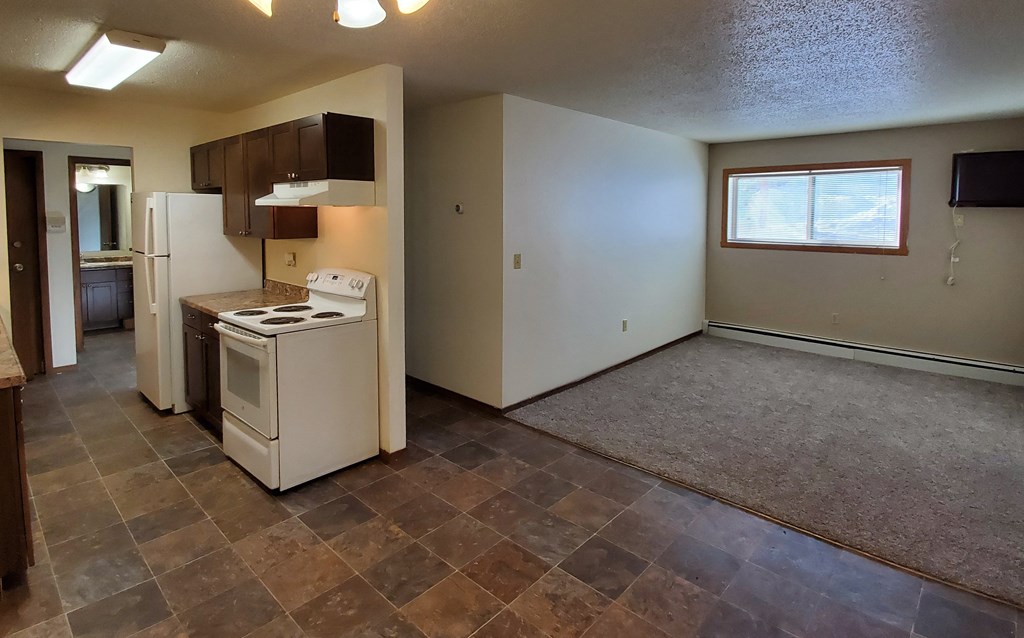 an empty kitchen and living room with a stove and refrigerator. Fargo, ND Brookfield Apartments
