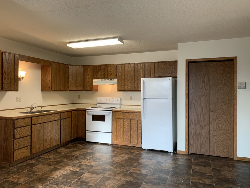 an empty kitchen with a refrigerator and a sink. Fargo, ND Brookfield Apartments