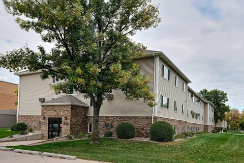 an apartment building with a tree in front of it. Fargo, ND Brownstone Apartments