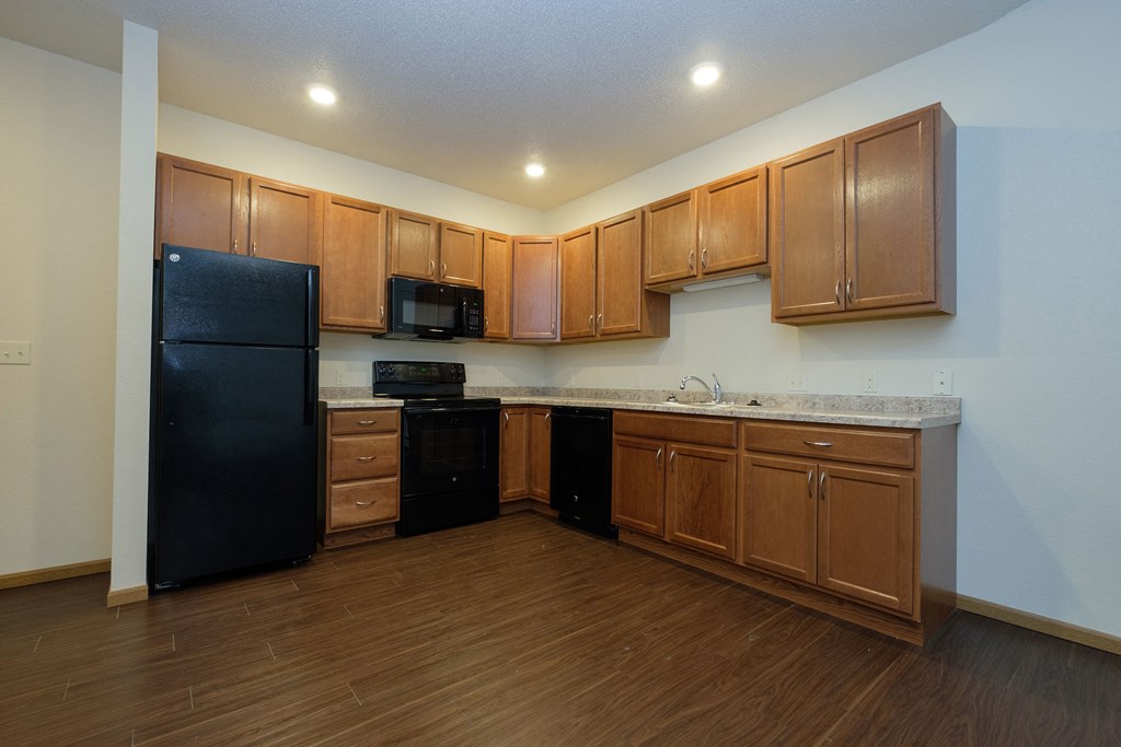 a kitchen with wooden cabinets and a black refrigerator. Fargo, ND North Sky Apartments