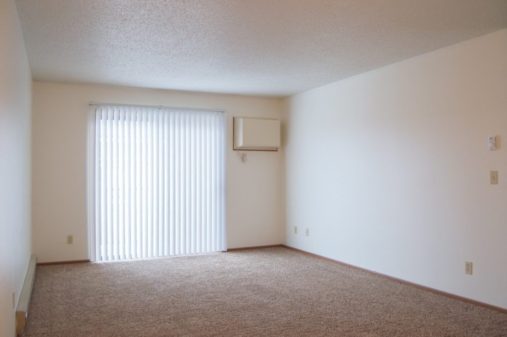 Fargo, ND Candlelight Apartments | Living the living room of an apartment with a window and blinds. Fargo, ND Candlelight Apartments